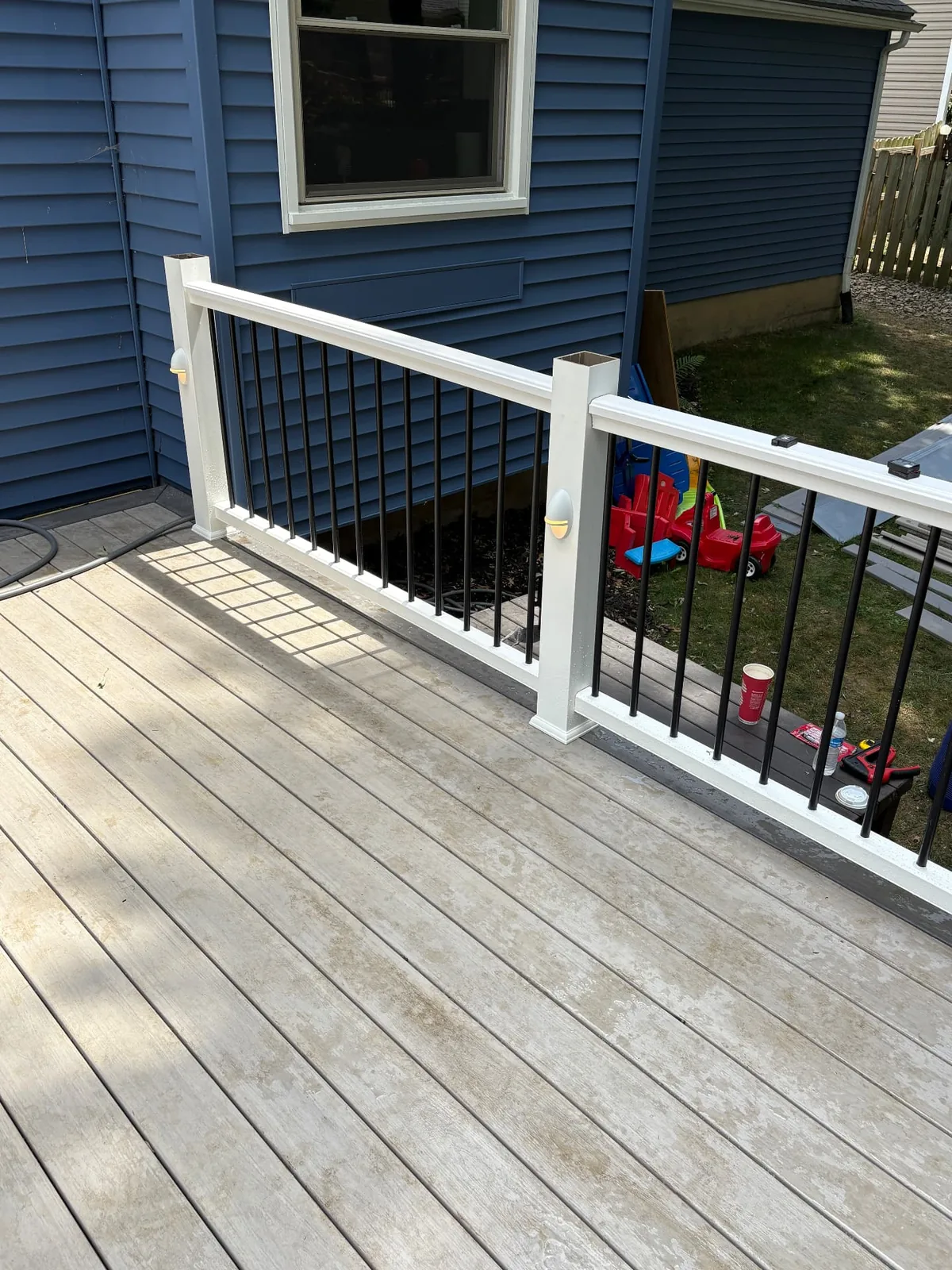 Composite deck and railing installed beside a blue-sided home