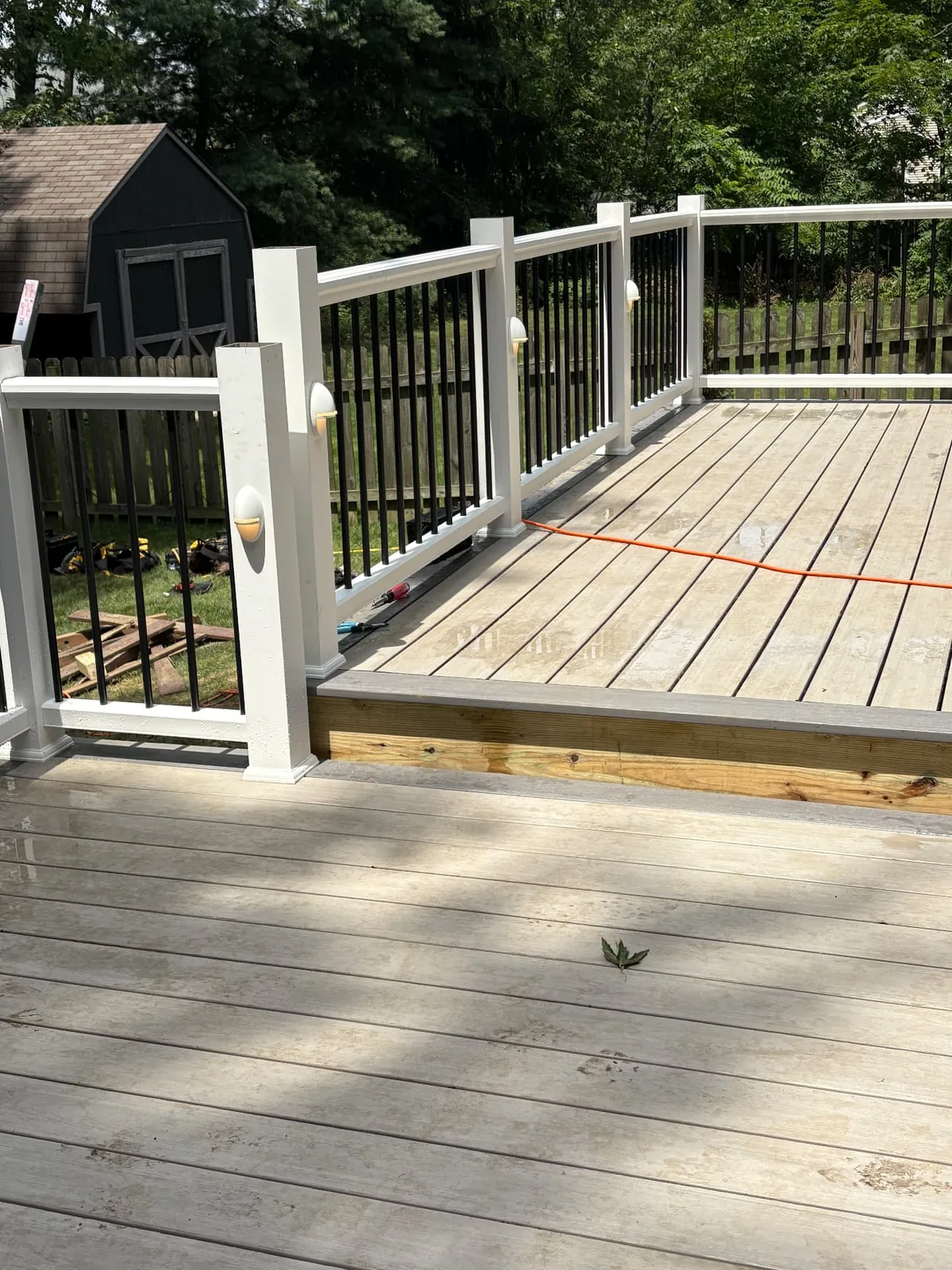 Corner detail of white deck posts with black railing balusters