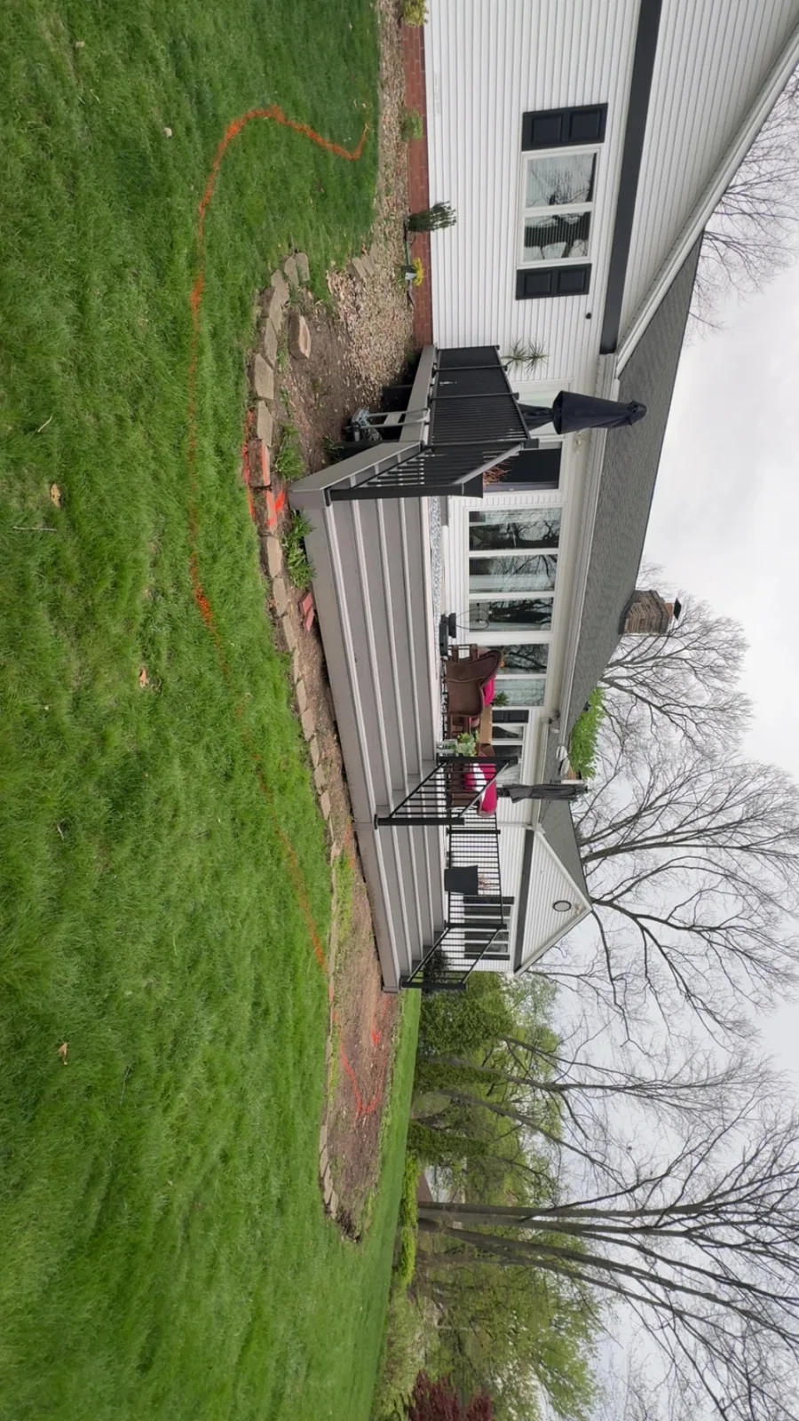 Wide view of a low composite backyard deck with dark railings