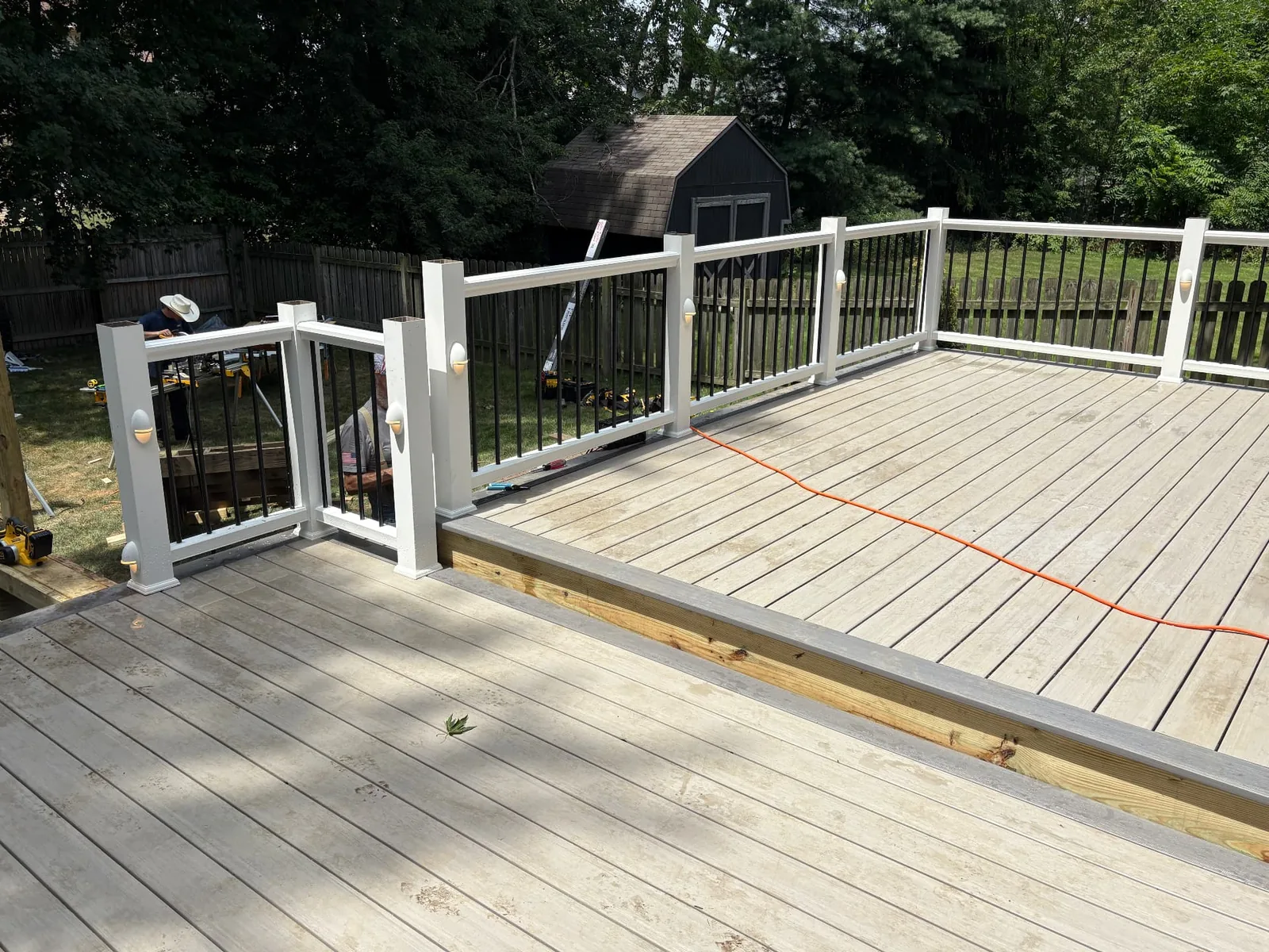 Wide view of a light composite deck with white posts and black railings