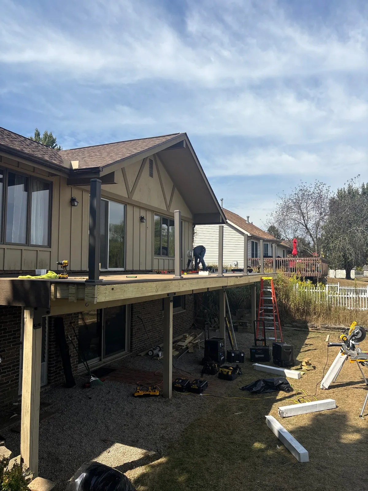 Raised backyard deck under construction with support posts and tools visible